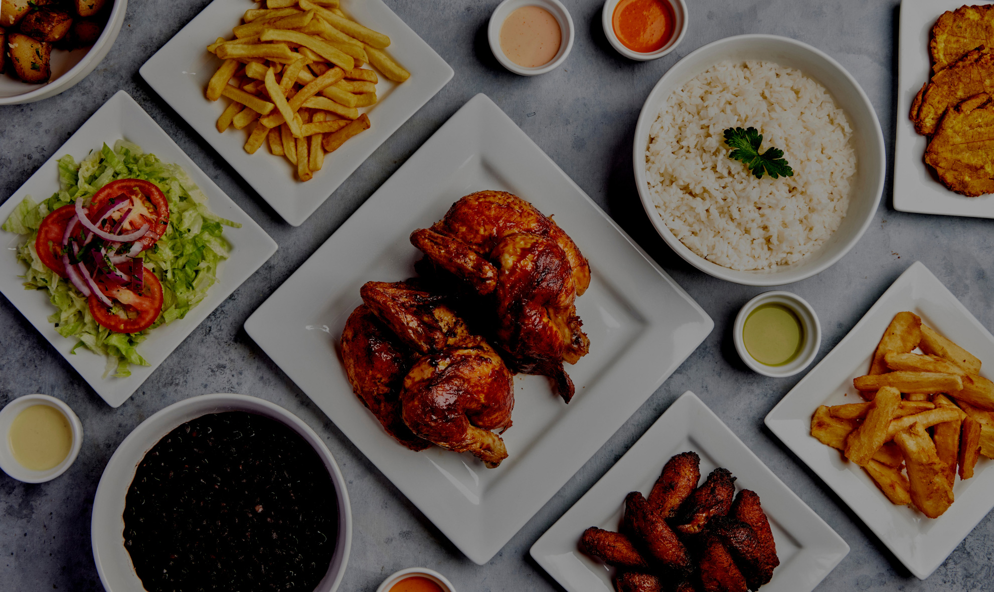 Plates of food. Whole chicken, fries, salad, rice, wings, and sauces